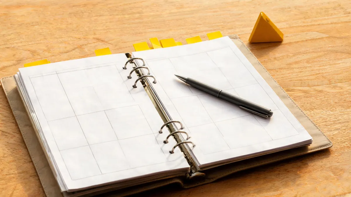 Open reference binder with sponsorship term definitions on a cream desk surface, bold yellow geometric triangle bookmark tabs, charcoal pen resting on the page